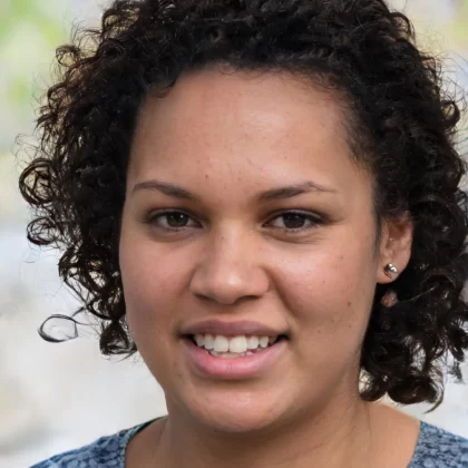 A headshot of a smiling woman with short, dark hair